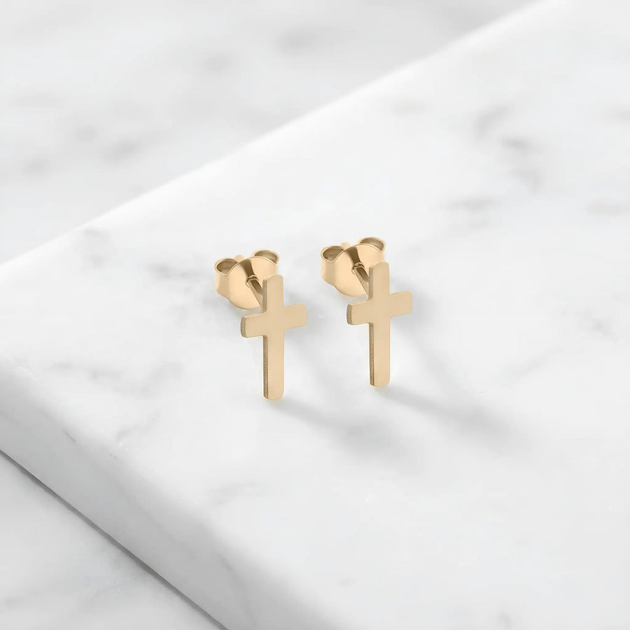Cercei aur 14K stud cu cruce latină plină — pereche pe fundal de marmură albă, două cruci simple cu brațul vertical mai lung, finisaj oglindă, prindere fluturaș push-back