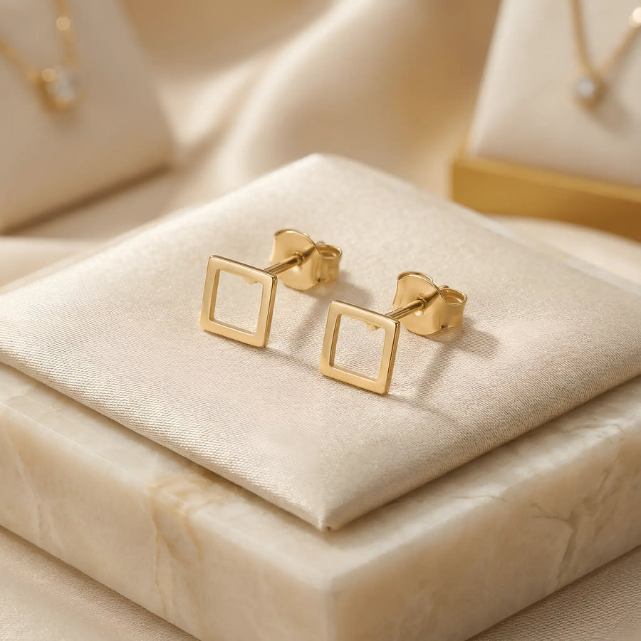 Cercei aur 14K stud cu pătrat outline 6x6mm — pereche pe pernuță de mătase crem cu marmură albă, cadru pătrat subțire fără umplutură, finisaj oglindă, prindere fluturaș push-back