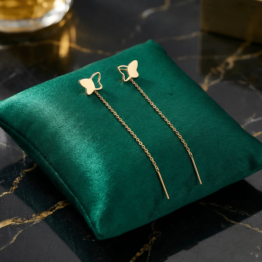 Cercei aur 14K threader fluture profil cu aripă fragmentată — pereche asimetrică pe pernă verde catifea, fluture plin și fluture cu aripă spartă