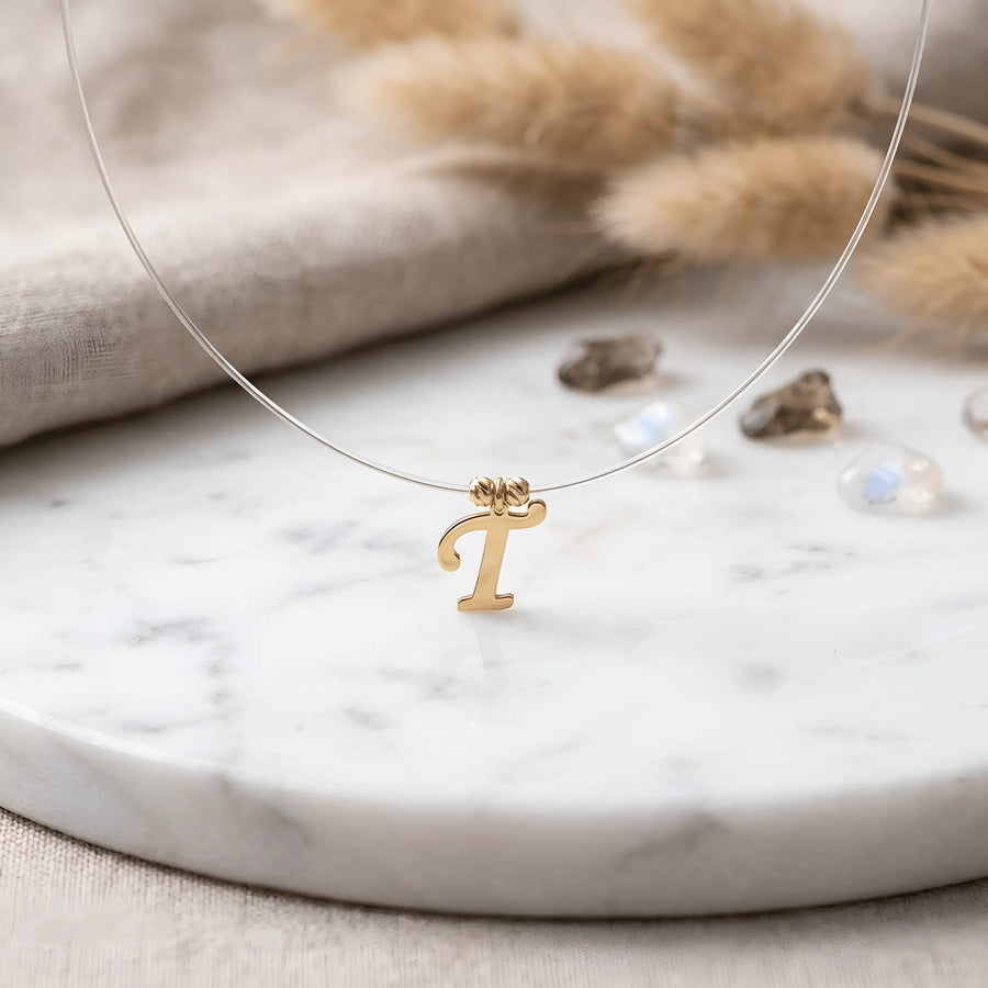 Colier aur 14K cu pandantiv litera T cursivă pe fir transparent — model floating