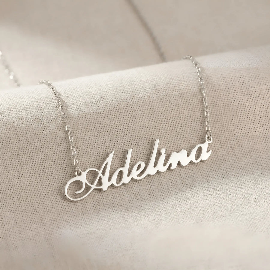 Lănțișor argint 925 rodiat cu numele Adelina, pandantiv decupat 42x10 mm font cursiv inițiala A cu buclă jos-stânga, lanț anchor 46 cm pe textil natural ivory tip in cu pliuri
