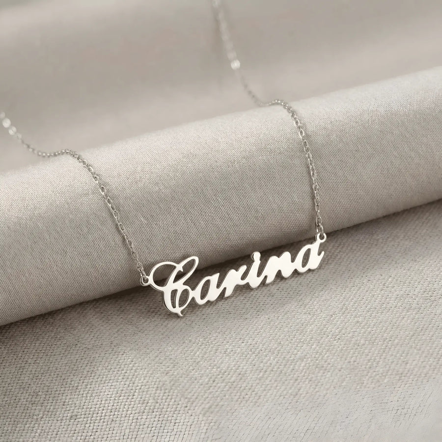 Lănțișor argint 925 rodiat cu numele Carina, pandantiv decupat 38.5x10 mm font cursiv inițiala C deschisă, lanț anchor 46 cm pe textil natural ivory tip in