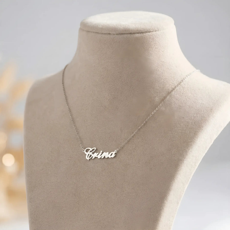 Lănțișor argint 925 rodiat cu numele Crina, pandantiv decupat 31x10 mm font cursiv, lanț anchor 46 cm pe bust expozițional bej