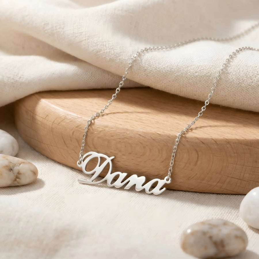 Lănțișor argint 925 rodiat personalizat cu numele Dana decupat în scriere cursivă elegantă cu D mare buclat pe textil alb cu lemn rotund și pietre, lanț subțire alb-platinat