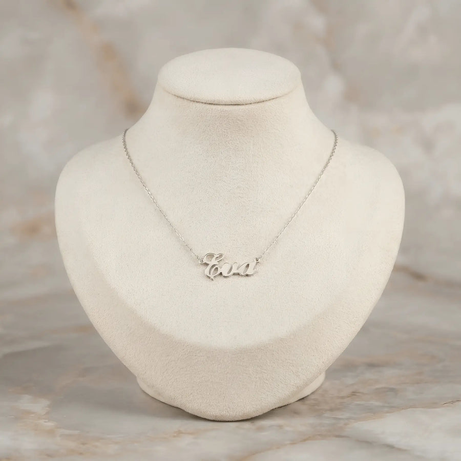 Lănțișor argint 925 rodiat cu numele Eva, pandantiv decupat 27x10 mm font cursiv inițiala E cu buclă verticală, lanț anchor 46 cm pe bust expozițional bej