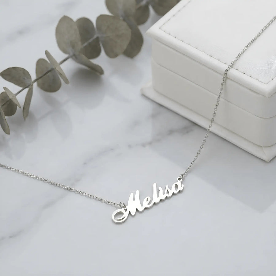 Lănțișor argint 925 rodiat cu numele Melisa, pandantiv decupat 38.5x10 mm font cursiv, lanț anchor 46 cm, lângă cutie cadou albă