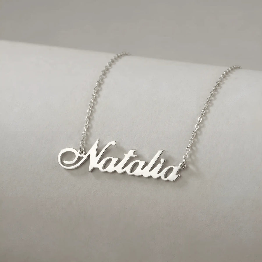 Lănțișor argint 925 rodiat cu numele Natalia, pandantiv decupat 42x10 mm font cursiv inițiala N cu diagonală descendentă, lanț anchor 46 cm pe bust expozițional ivory mat