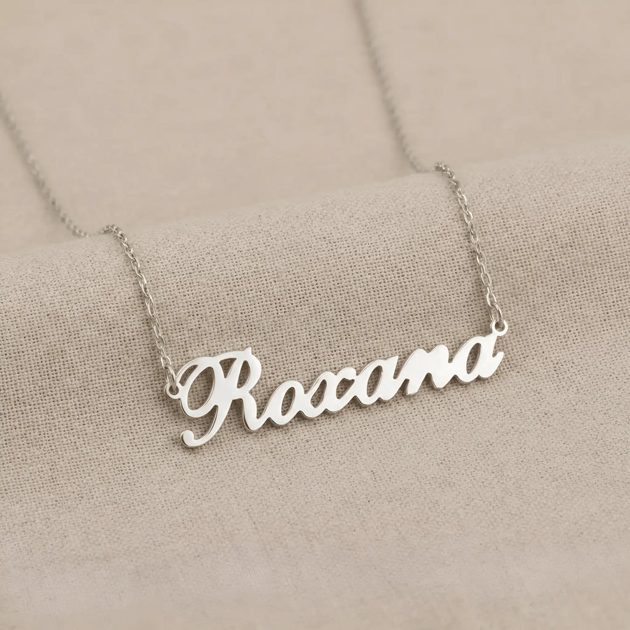 Lănțișor argint 925 rodiat personalizat cu numele Roxana decupat în scriere cursivă elegantă pe lanț subțire alb-platinat, ambianță textilă caldă bej