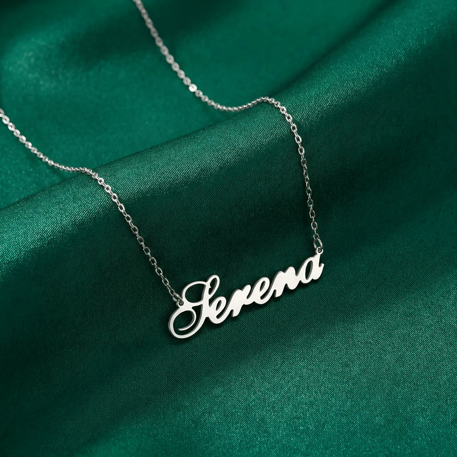 Lănțișor argint 925 rodiat personalizat cu numele Serena decupat în scriere cursivă elegantă cu S ondulat pe drapaj satin verde smarald, lanț subțire alb-platinat