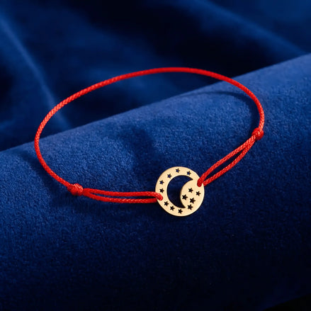 Brățară aur 14K cu șnur roșu și pandantiv bănuț lună și stele 14×14 mm