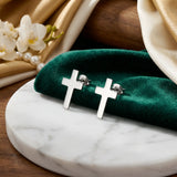 Cercei argint 925 rodiat stud cu cruce latină plină 10x6.5mm — pereche pe placă de marmură albă cu pânză verde-emeraldă și flori de orhidee albă, perle și satin auriu pe fundal, finisaj oglindă alb-platinat