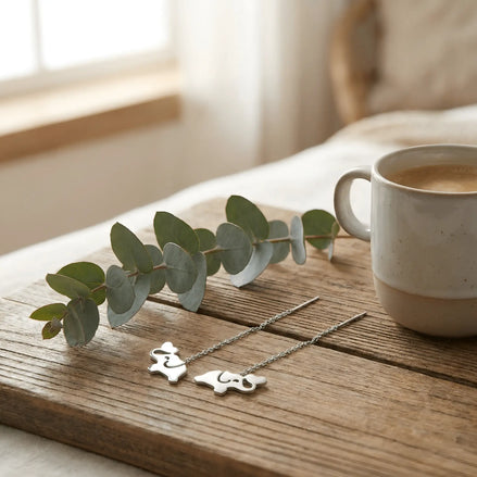 Cercei argint 925 cu elefant threader pe lemn rustic alături de cană cafea și ramuri eucalipt – atmosferă boho relaxată