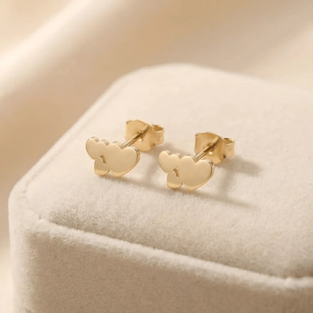 Cercei aur 14K stud cu trei inimi pline gradient — pereche pe cutie velvet crem, trei inimi aliniate orizontal mică-medie-mare, finisaj oglindă, dimensiune 10x5.5mm