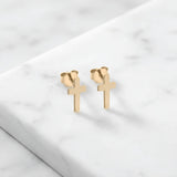 Cercei aur 14K stud cu cruce latină plină — pereche pe fundal de marmură albă, două cruci simple cu brațul vertical mai lung, finisaj oglindă, prindere fluturaș push-back