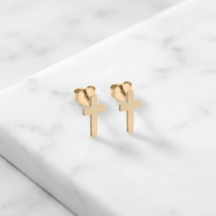 Cercei aur 14K stud cu cruce latină plină — pereche pe fundal de marmură albă, două cruci simple cu brațul vertical mai lung, finisaj oglindă, prindere fluturaș push-back
