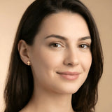 Cercei aur 14K stud cruce latină — close-up perechii cu fluturașii vizibili, cruce plină simplă fără ornament