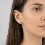 Cercei aur 14K diamant stilizat purtați pe ureche — model dama păr brunet, formă diamant cu fațete decupate vizibile pe lobul urechii