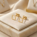 Cercei aur 14K stud cu pătrat outline 6x6mm — pereche pe pernuță de mătase crem cu marmură albă, cadru pătrat subțire fără umplutură, finisaj oglindă, prindere fluturaș push-back