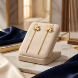 Cercei aur 14K threader cu cluster trio stele suprapuse 9,7mm — pereche pe suport velvet bej cu placă marmură albă, draperie satin albastru-navy și crem pe fundal, cluster cu stea mare centrală și 2 stele mici în față, lanț 6cm cu tijă-bară, finisaj oglindă pe aur galben