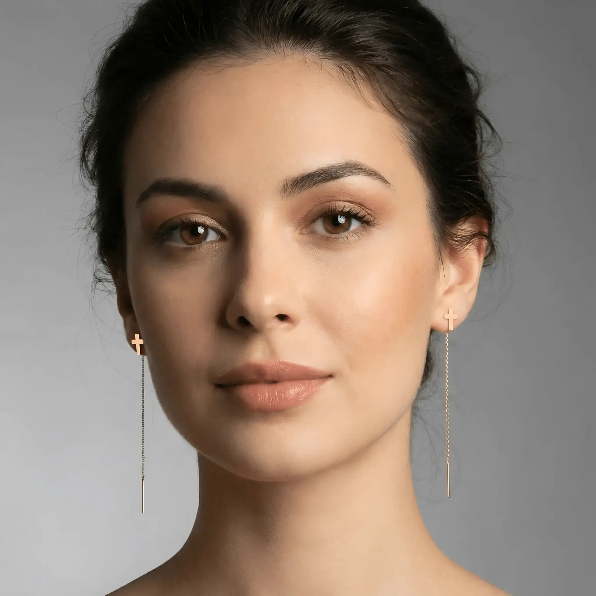 Cercei aur 14K threader cruce mică purtați pe ureche — model dama păr brunet prins, cruce mică deasupra lobului și lănțișor lung pe spate