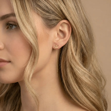 Cercei aur 14K threader fluture decupat purtați pe ureche — model dama păr blond, fluture mic cu aripi decupate deasupra lobului, lanț pe spate