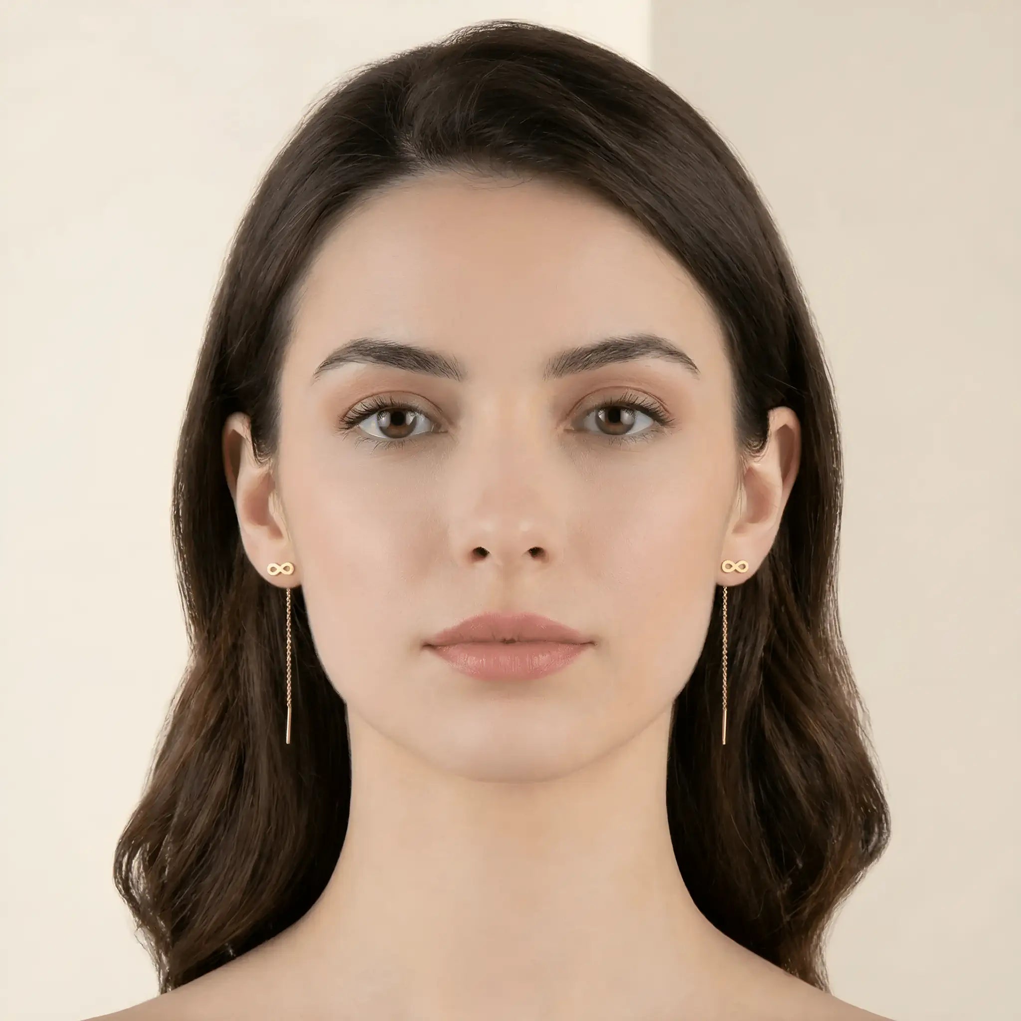 Cercei aur 14K threader infinit purtați pe ureche — model dama păr brunet, simbol infinit deasupra lobului și lănțișor delicat pe spate