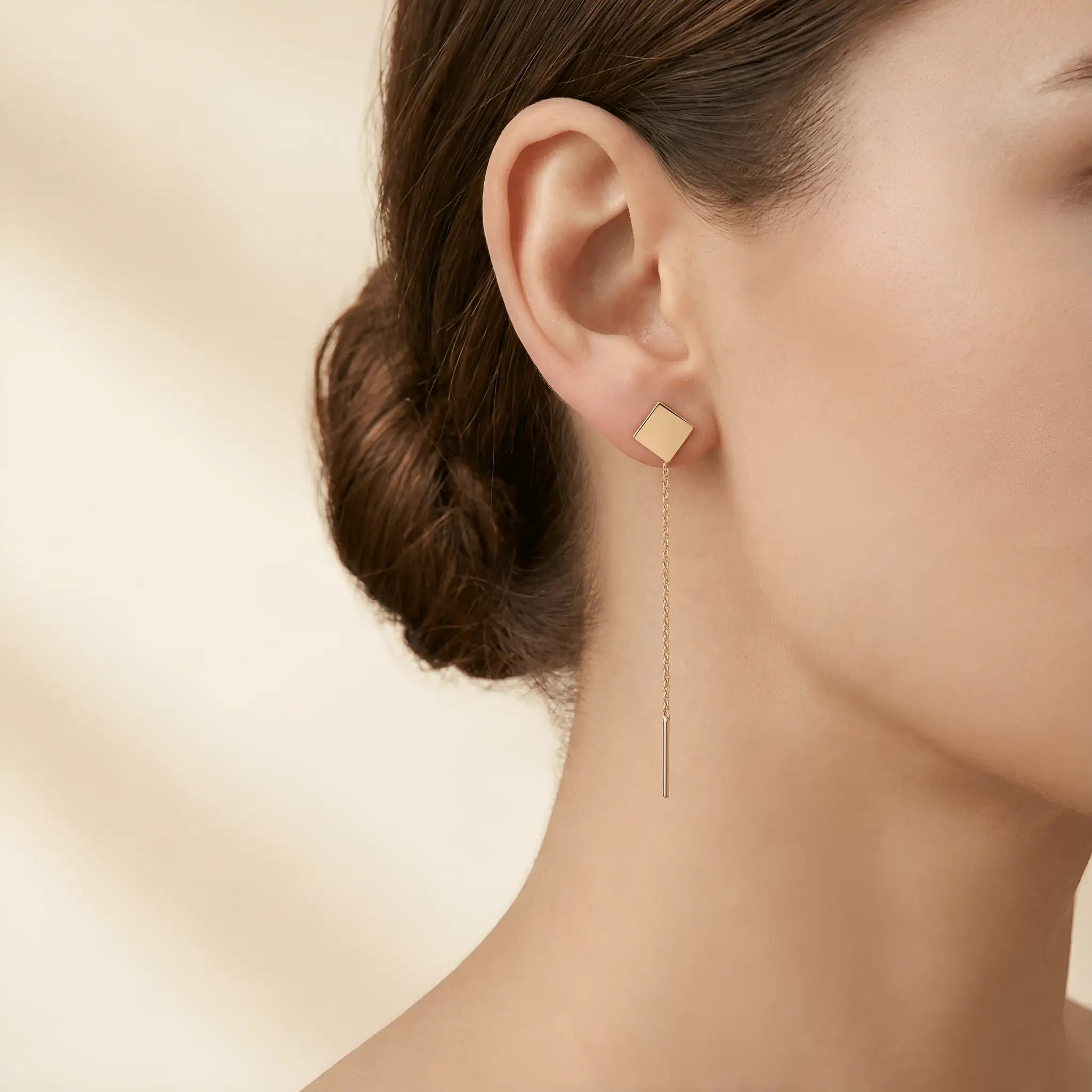 Cercei aur 14K threader pătrat plin purtați pe ureche — model dama păr brunet prins coc, pătrat geometric deasupra lobului și lănțișor lung pe spate
