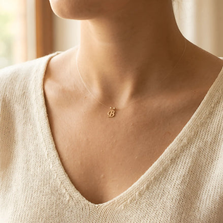 Colier aur 14K litera B — purtat pe decolteu V cardigan crem-ivoire, efect floating
