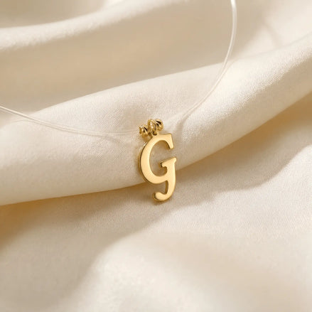 Colier aur 14K cu pandantiv litera G roman lapidar pe fir transparent — model floating