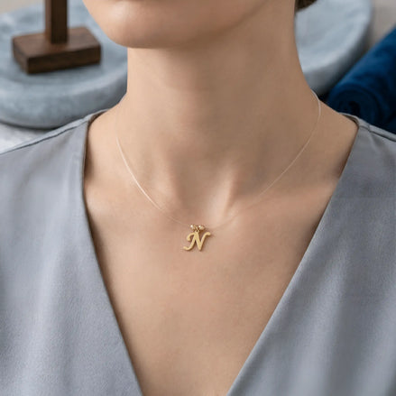 Colier aur 14K litera N — purtat pe decolteu V bluză satinată gri, efect floating