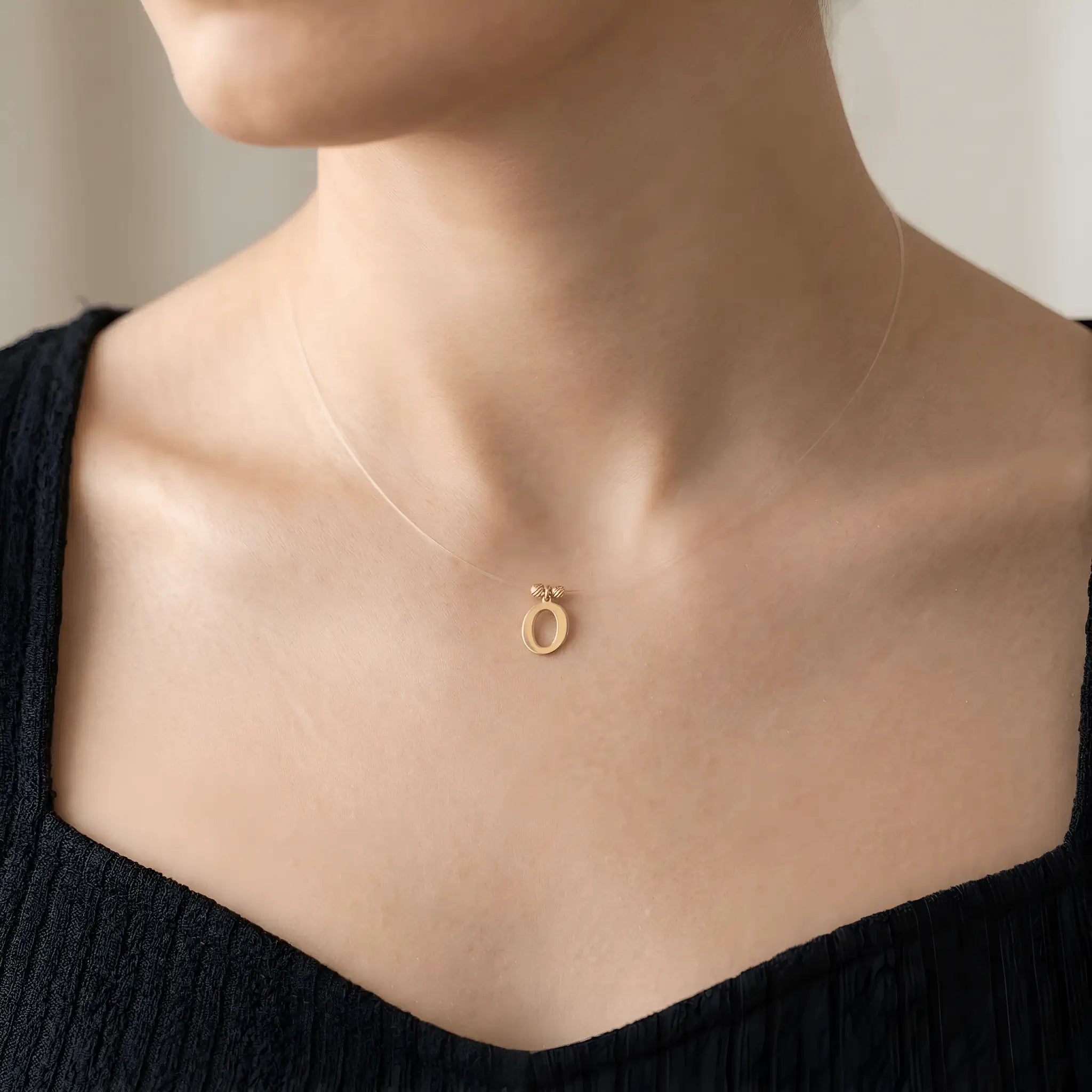 Colier aur 14K litera O — purtat pe decolteu pătrat top negru, efect floating