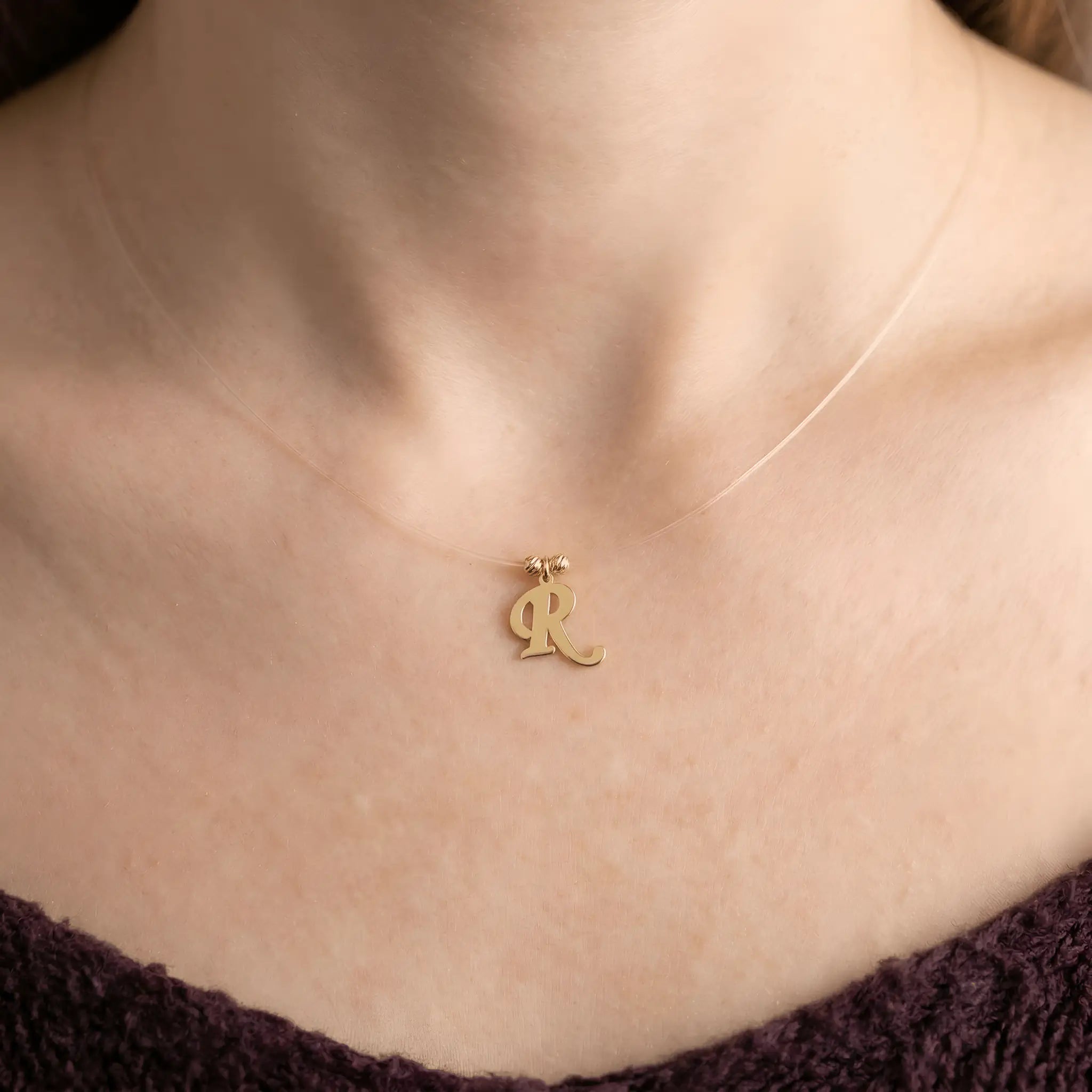 Colier aur 14K litera R — purtat pe decolteu, efect floating pe pielea modelei