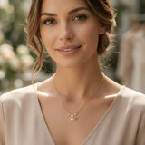 Damă tânără purtând colier aur 14K cu pandantiv lotus pe top crem cu decolteu V, lumină naturală exterior cu vegetație înflorită