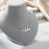 Lănțișor argint 925 rodiat personalizat cu numele Ada decupat în scriere cursivă elegantă cu coadă caligrafică ornamentală pe bust display gri velvet