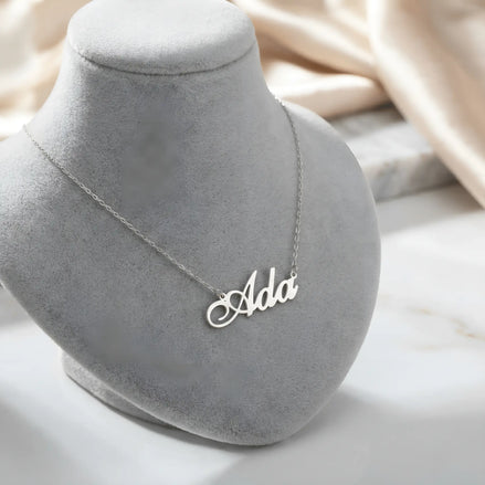 Lănțișor argint 925 rodiat personalizat cu numele Ada decupat în scriere cursivă elegantă cu coadă caligrafică ornamentală pe bust display gri velvet