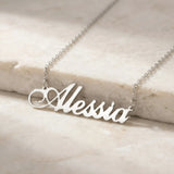 Lănțișor argint 925 rodiat personalizat cu numele Alessia decupat în scriere cursivă cu flourish ornamental, pe lanț subțire alb-platinat, ambianță marmură caldă