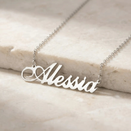 Lănțișor argint 925 rodiat personalizat cu numele Alessia decupat în scriere cursivă cu flourish ornamental, pe lanț subțire alb-platinat, ambianță marmură caldă