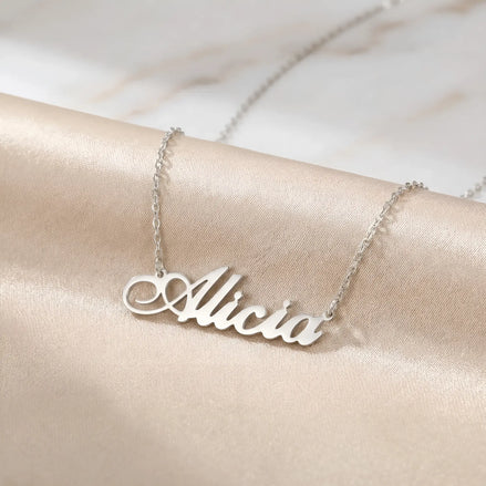 Lănțișor argint 925 rodiat personalizat cu numele Alicia decupat în scriere cursivă elegantă cu A buclat pe drapaj satin roz piersică, lanț subțire alb-platinat