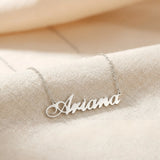 Lănțișor argint 925 rodiat personalizat cu numele Ariana decupat în scriere cursivă elegantă pe lanț subțire alb-platinat, ambianță textilă caldă crem