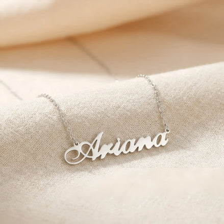 Lănțișor argint 925 rodiat personalizat cu numele Ariana decupat în scriere cursivă elegantă pe lanț subțire alb-platinat, ambianță textilă caldă crem