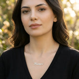 Damă tânără purtând lănțișor argint 925 rodiat cu numele Bianca script, peste top negru cu decolteu V, lumină naturală apus în exterior