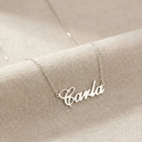 Lănțișor argint 925 rodiat cu numele Carla, pandantiv decupat 34.5x10 mm font cursiv inițiala C deschisă, lanț anchor 46 cm pe textil natural bej tip in