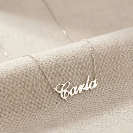 Lănțișor argint 925 rodiat cu numele Carla, pandantiv decupat 34.5x10 mm font cursiv inițiala C deschisă, lanț anchor 46 cm pe textil natural bej tip in