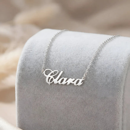 Lănțișor argint 925 rodiat cu numele Clara, pandantiv decupat 34.5x10 mm font cursiv inițiala C deschisă, lanț anchor 46 cm pe textil velvet gri-deschis