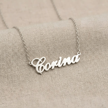 Lănțișor argint 925 rodiat cu numele Corina, pandantiv decupat 38.5x10 mm font cursiv inițiala C deschisă, lanț anchor 46 cm pe textil natural