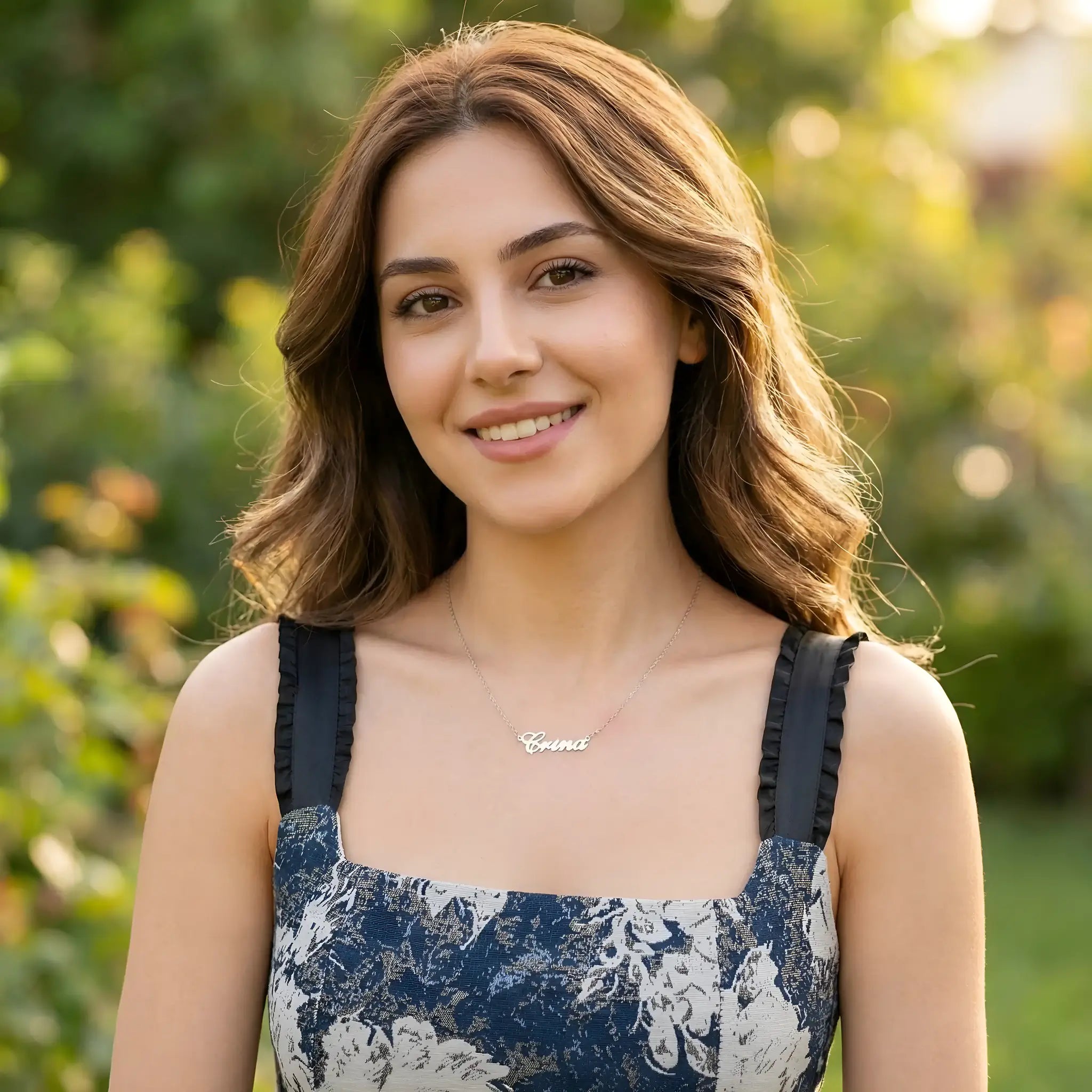 Damă tânără cu păr castaniu purtând lănțișor argint 925 rodiat Crina peste top din in cu imprimeu floral navy, exterior grădină