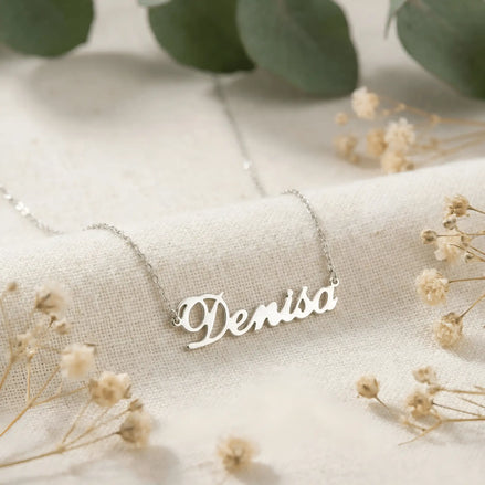 Lănțișor argint 925 rodiat cu numele Denisa, pandantiv decupat 38.5x10 mm font cursiv inițiala D cu curbă închisă, lanț anchor 46 cm pe textil ivory mat cu eucalypt și gypsophila uscată