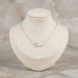 Lănțișor argint 925 rodiat cu numele Eva, pandantiv decupat 27x10 mm font cursiv inițiala E cu buclă verticală, lanț anchor 46 cm pe bust expozițional bej