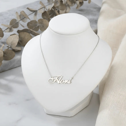 Lănțișor argint 925 rodiat personalizat cu numele Flori decupat în scriere cursivă elegantă cu F și coadă caligrafică pe bust display alb cu eucalipt uscat, lanț subțire alb-platinat
