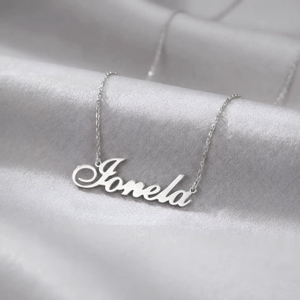 Lănțișor argint 925 rodiat cu numele Ionela, pandantiv decupat 38.5x10 mm font cursiv inițiala I cu coadă subțire descendentă, lanț anchor 46 cm pe textil satinat alb